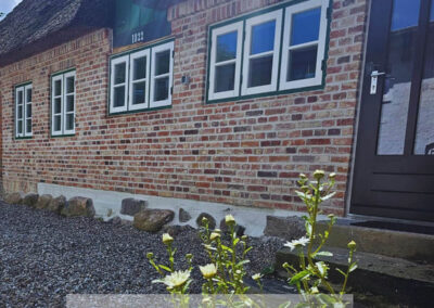 Sanierte Ziegelfassade am Reetdachhaus